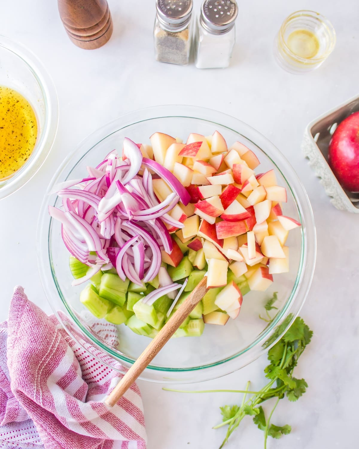 salad ingredients combined in clear bowl.
